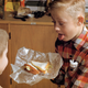 Young boy holds a sandwich and sticks tongue out at another boy